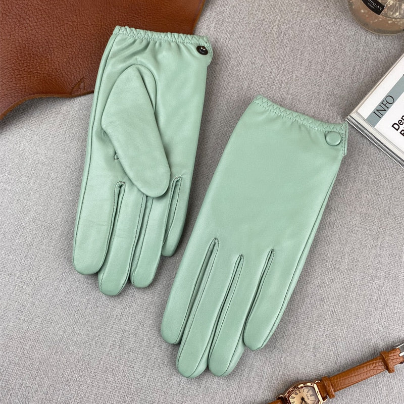 Pair of mint green leather gloves laid flat, showing buttoned cuffs and stitched fingers