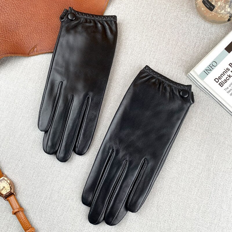 Pair of black leather gloves laid flat, showing stitched fingers and snap-button cuffs