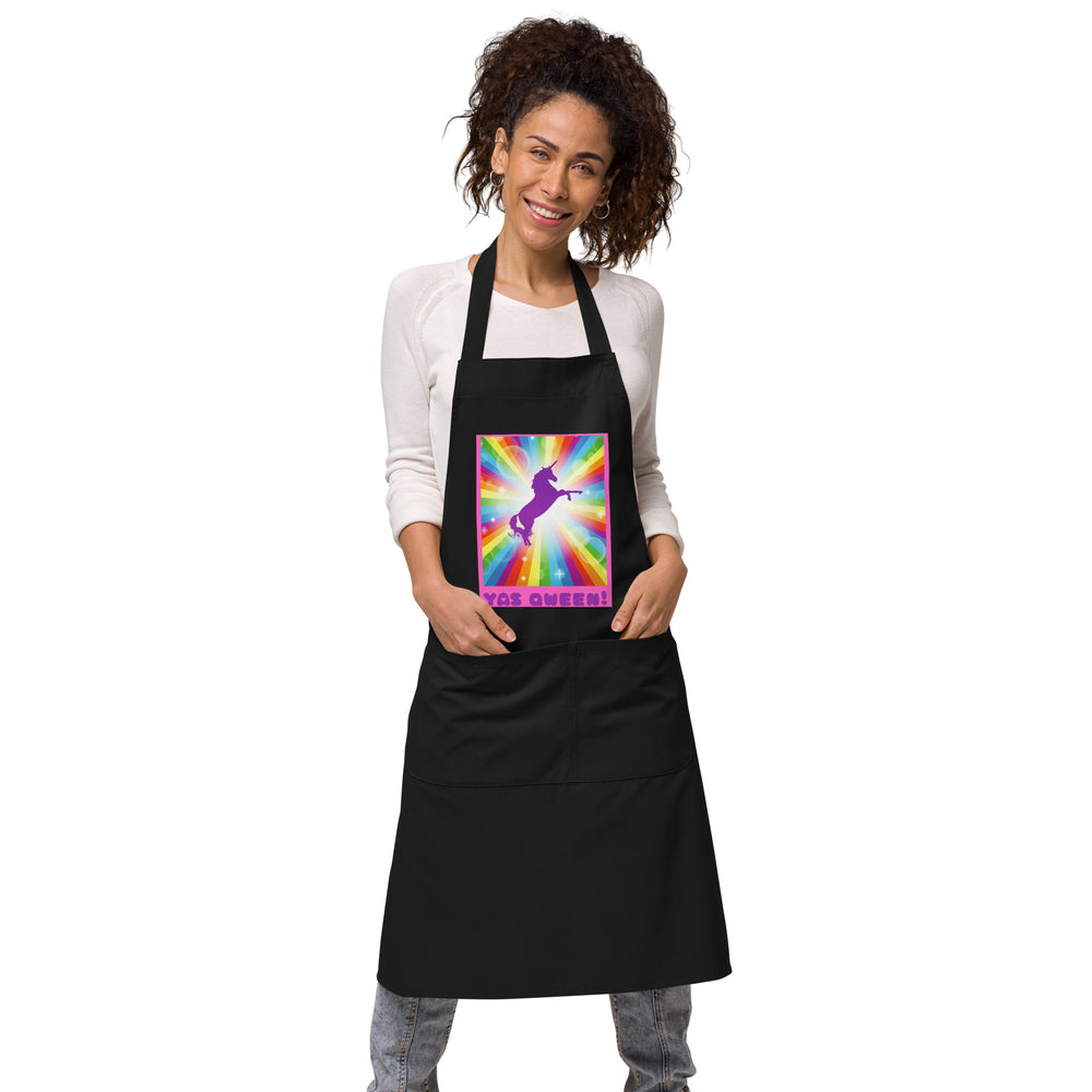 Model wearing a black apron with a rainbow unicorn graphic and “YAS QWEEN!” text
