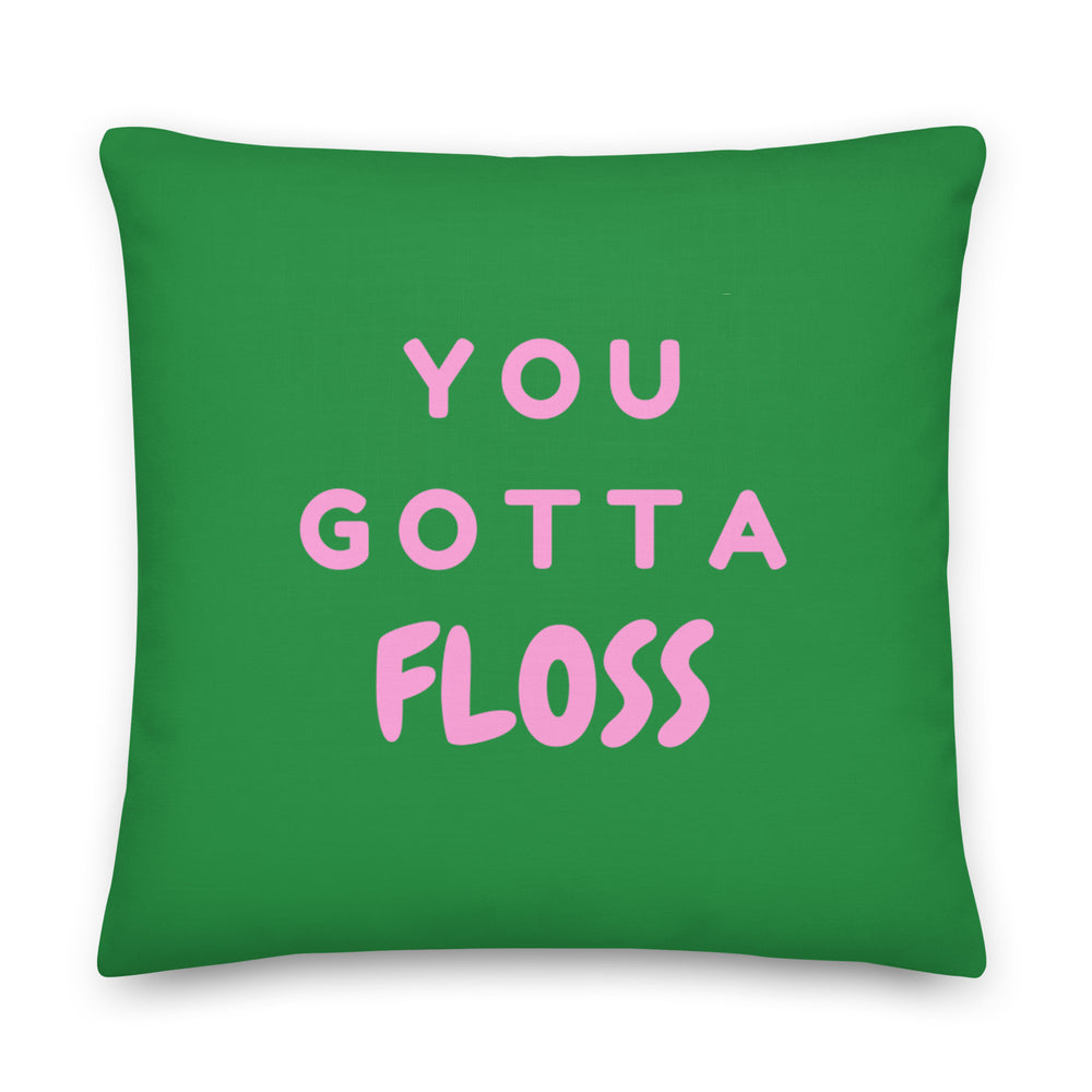 Green square pillow with pink lettering reading “YOU GOTTA FLOSS”