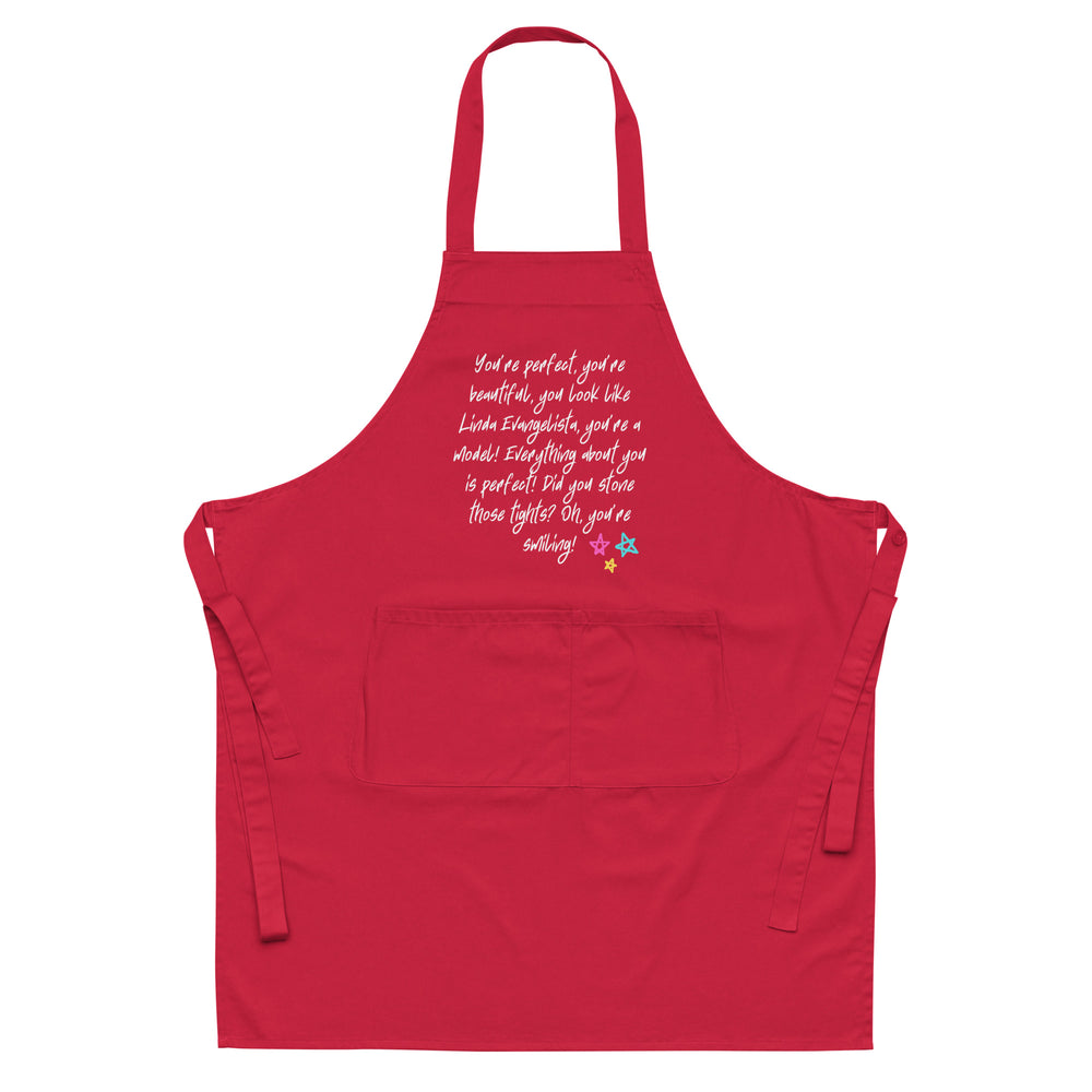 Front-view red apron with neck loop, waist ties, pocket, and white Linda Evangelista quote