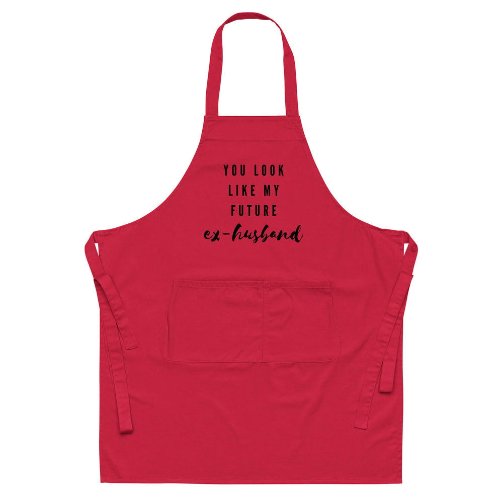 Front view of a red apron with neck and waist ties, pocket, and text “YOU LOOK LIKE MY FUTURE ex-husband.”