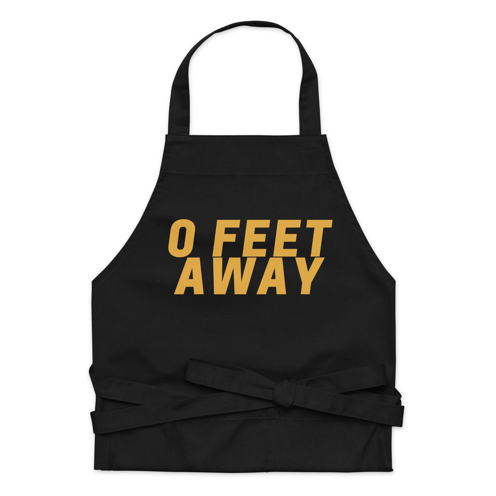 Front view of a black apron with gold “0 FEET AWAY” lettering and waist ties
